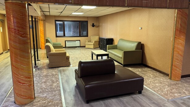 A spacious room with a sectional sofa, a small table, and two patterned armchairs. - HILLTOP INN (Barre)