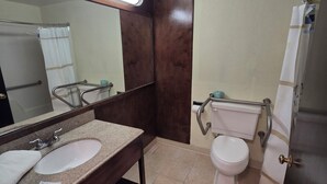 A bathroom with a double sink, a toilet, a mirror, and a shower curtain. - HILLTOP INN (Barre)