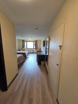 A hotel room with a bed, a desk, a chair, a TV, and a window with curtains. - HILLTOP INN (Barre)