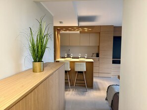 Une cuisine moderne avec des meubles en bois, un îlot central doté de tabourets et une plante en pot.