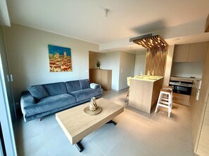 Ein modernes Wohnzimmer mit einer Couch, einem Couchtisch und einem Essbereich mit Stühlen und einer kleinen Kochinsel.
