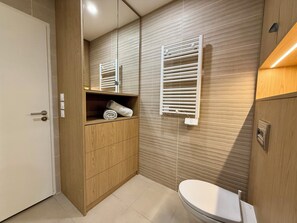 Een moderne badkamer met een houten wastafelmeubel, een handdoekhouder en een toilet.