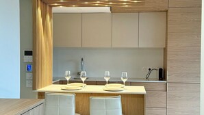 Uma cozinha moderna com uma ilha central, duas cadeiras brancas e um espelho grande.