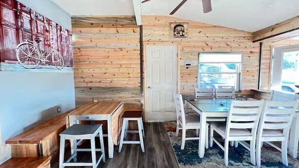 Ein Essbereich mit Holzbalkendecke, weißen Stühlen und einem Tisch.