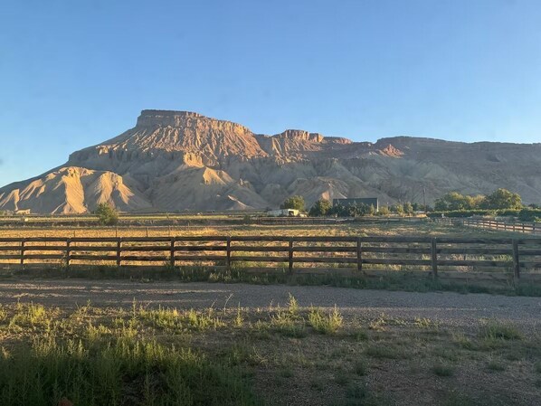 A rural landscape with a prominent hill, a wooden fence, and a clear sky.