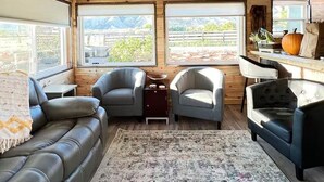 Ein gemütliches Interieur mit Holzbalkendecke, einem Ledersofa, zwei Sesseln, einem Teppich und einem Tisch mit Kürbisdekoration.