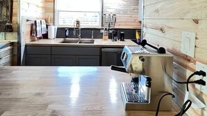 Eine moderne Küche mit Holzwänden, einer Edelstahl-Arbeitsplatte und einer integrierten Espressomaschine.