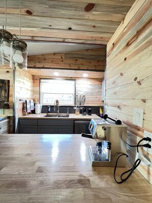 Eine moderne Küche mit Holzwänden, einer Edelstahl-Arbeitsplatte und einer integrierten Espressomaschine.