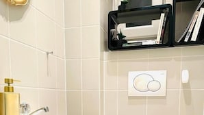 A bathroom with a white sink, toilet, and a shelf with books and toiletries.