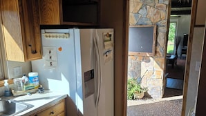 Una cocina con armarios de madera, un refrigerador blanco y una pared de piedra.