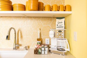 A kitchen with a coffee maker, a bottle of Monin syrup, and a bag of Quills coffee blend. - Hollyhock Suite 313: 5 beds/2 bath (Louisville)