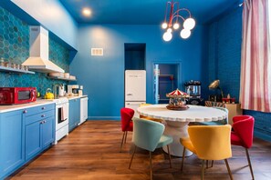 A kitchen with blue cabinets, a microwave, a stove, and a dining area with a carousel table. - Hollyhock Suite 313: 5 beds/2 bath (Louisville)