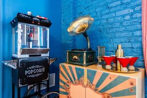 Eine alte Popcornmaschine und ein Grammophon auf einer Theke, mit einer Wand aus blauen Ziegeln im Hintergrund.