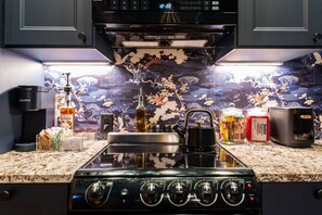 A kitchen with a gas stove, a kettle, a coffee maker, and a microwave. - Hollyhock Suite 310: 2 beds/1 bath (Louisville)