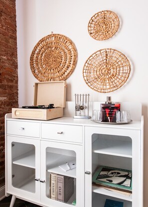 A white cabinet with a record player, decorative woven circles, and books. - Hollyhock Suite 307: 3 bed /2 bath (Louisville)