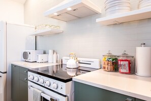 A modern kitchen with a stove, microwave, toaster, and kettle on the countertop. - Hollyhock Suite 307: 3 bed /2 bath (Louisville)