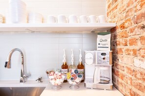 A kitchen area with a coffee machine, a coffee bag, and a bowl of snacks. - Hollyhock Suite 307: 3 bed /2 bath (Louisville)