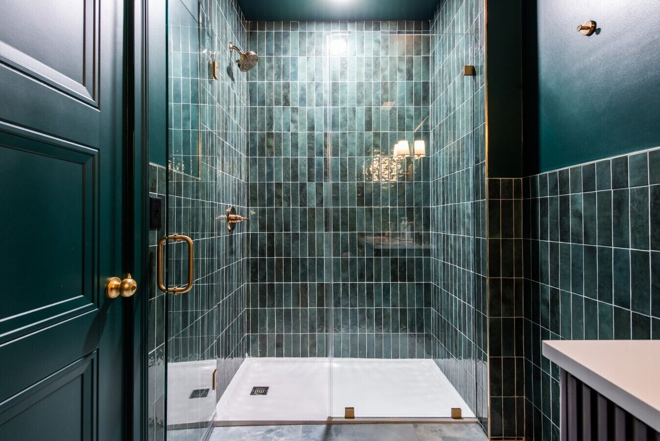 A bathroom with a tiled shower area, a door with a handle, and a light fixture.