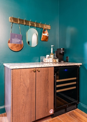 A bathroom with a wooden cabinet, a sink, a mirror, and a towel rack. - Hollyhock Suite 311: 1 bed/1 bath (Louisville)