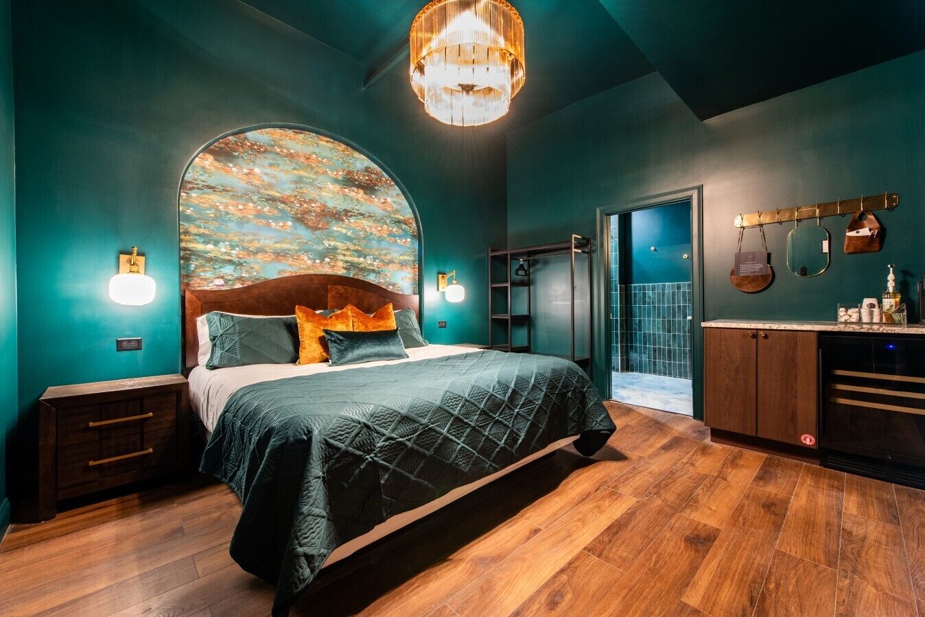 Une chambre à coucher avec un grand lit, une tête de lit en bois, une œuvre d’art accrochée au mur et une armoire intégrée.