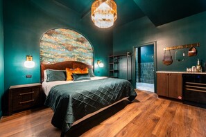 A bedroom with a large bed, a wooden headboard, a wall-mounted artwork, and a built-in wardrobe. - Hollyhock Suite 311: 1 bed/1 bath (Louisville)