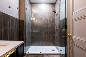 Ein modernes Badezimmer mit einer Duschkabine aus Glas, einem weißen Waschbecken und einer Tür mit goldener Griff.