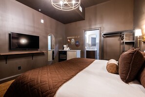 Ein Hotelzimmer mit einem Bett, einem Fernseher, einem Spiegel, einem Waschbecken und einer Tür.