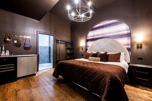 Ein modernes Schlafzimmer mit einem großen Bett, einem Schminktisch mit Pflegeprodukten und Blick auf den Himmel durch ein rundes Fenster.