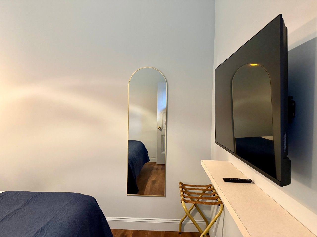 Ein Hotelzimmer mit Bett, Stuhl, Fernseher und Spiegel.