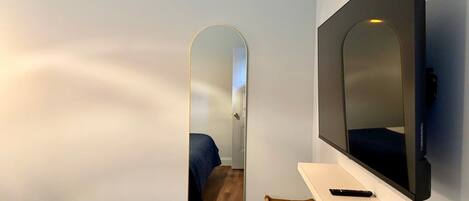 Ein Hotelzimmer mit Bett, Stuhl, Fernseher und Spiegel.