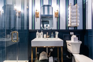 Un baño moderno con un espejo grande, un lavamanos blanco y un inodoro.