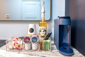 A kitchen counter with a coffee maker, a bottle of vanilla extract, a coffee grinder, and a coffee machine. - Hollyhock Suite 308: 2 beds/1 bath (Louisville)