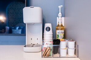 A coffee maker, a bottle of Monin French Vanilla syrup, and various coffee pods on a countertop. - Hollyhock Suite 306: 1 bed + 1 loft bed/1 bath (Louisville)
