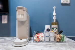 A coffee maker, a bottle of Monin Vanilla syrup, and various condiments on a marble countertop. - Hollyhock Suite 306: 1 bed + 1 loft bed/1 bath (Louisville)
