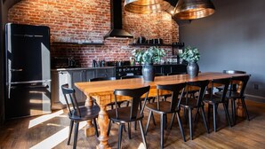 Une cuisine moderne avec un mur en briques, des appareils électroménagers en acier inoxydable et une table à manger en bois, assortie de chaises.