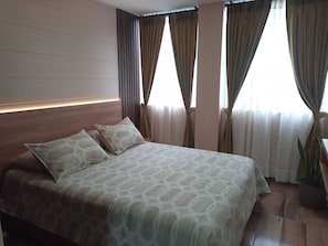 A hotel room with a large bed, a headboard, and a potted plant. - Casa Bella Suites Ibarra: Modern apartment in La Victoria, near the universities (Ibarra)