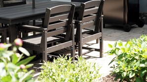 Eine Terrasse im Freien mit Tisch und Stühlen, einem Grill und einem blauen Sonnenschirm.