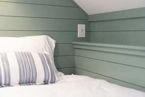 A bed with white bedding and a striped pillow in a room with green walls and a white ceiling. - Walk to Lake & Restaurants | Fire Table, Ping Pong, Shuffleboard | Sleeps 12 (Williams Bay)