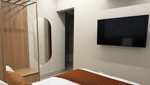 Ein Hotelzimmer mit Bett, Fernseher, Kleiderschrank und Spiegel.
