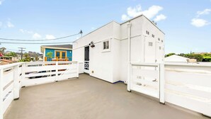 A rooftop with a white building, a blue structure with a red roof, and a clear sky. - Del Mar Studio - Walk to Beach (Del Mar)