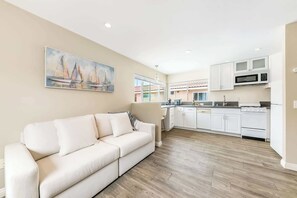 Ein modernes Wohnzimmer mit einem beigen Sofa und einem Gemälde von Segelbooten an der Wand.