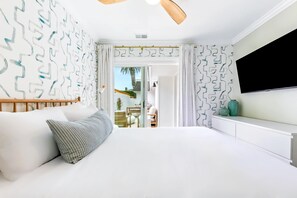 A modern bedroom with a large bed, a TV mounted on the wall, and a view of the outside through a glass door. - Designer Del Mar Escape , Beach, Dining & Shops (Del Mar)