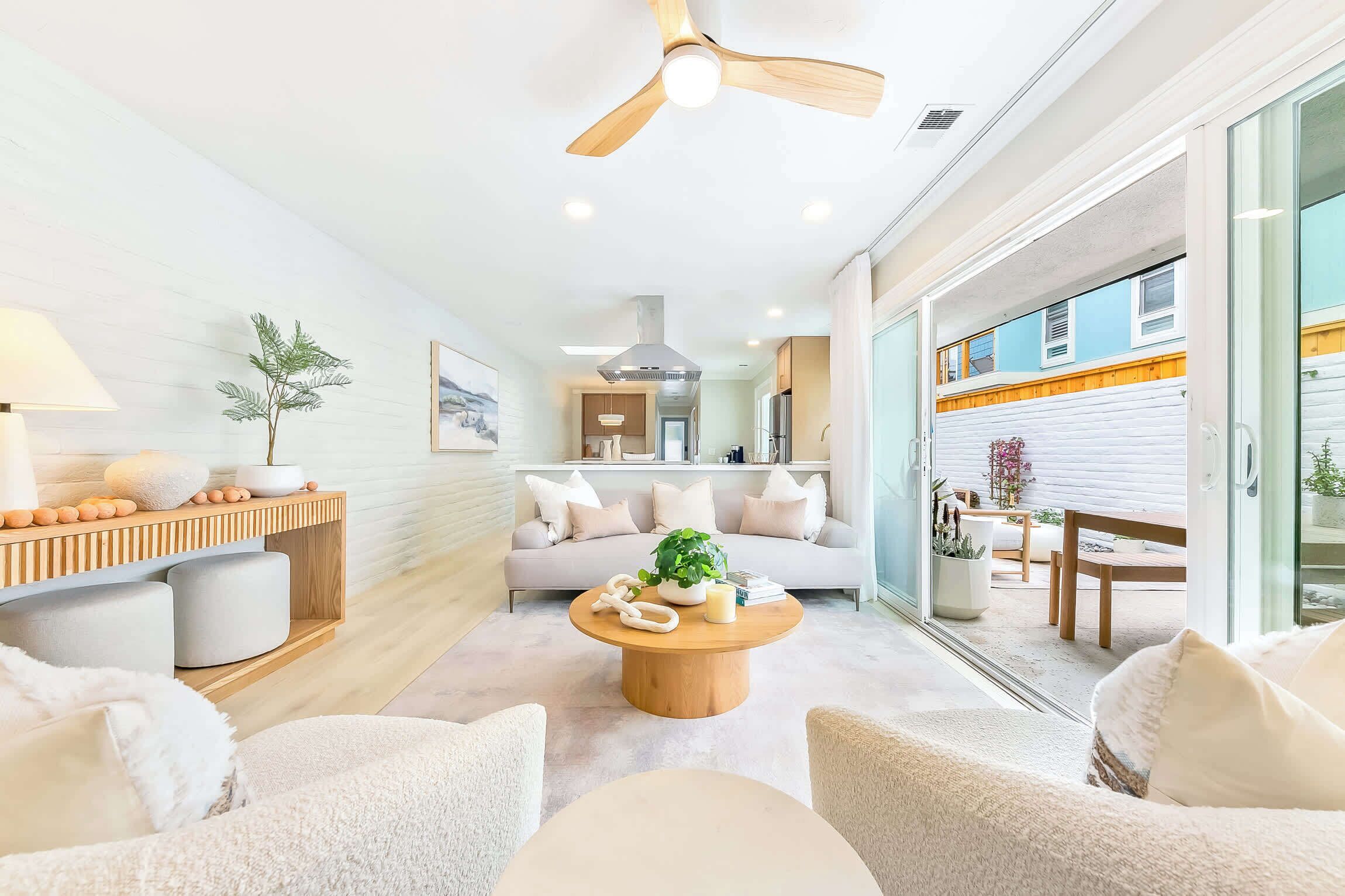 Un salon moderne avec un ventilateur de plafond, une table basse ronde en bois et un canapé agrémenté de coussins.