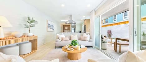 A modern living room with a ceiling fan, a round wooden coffee table, and a sofa with cushions.