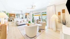 Una sala de estar moderna con un sofá, sillones, una mesa de centro y una zona de comedor con una mesa y sillas.