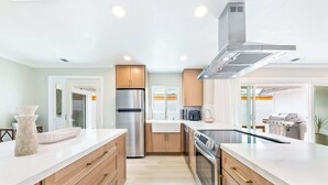 Una cocina moderna con un refrigerador de acero inoxidable, horno empotrado y extractor de humos.