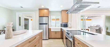 A modern kitchen with a stainless steel refrigerator, a built-in oven, and a range hood.