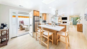 Una cocina moderna con una isla central, sillas de madera y horno empotrado.