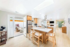 Eine moderne Küche mit einer zentralen Kochinsel, Holzkohle-Stühlen und einem eingebauten Backofen.