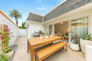 A patio with a wooden table and bench, surrounded by potted plants and a grill. - Designer Del Mar Escape , Beach, Dining & Shops (Del Mar)
